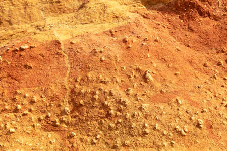 A vertical wall of yellow-orange ocher sandstone on the coast. Sand wall texture on a sunny day,...