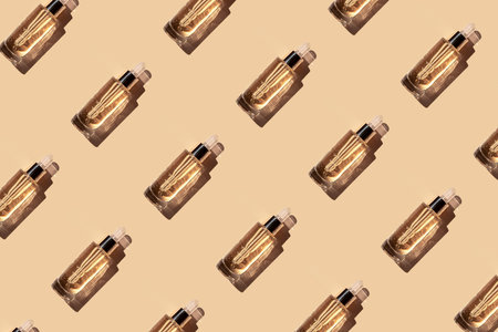 Seamless pattern diagonal beautiful transparent bottle cosmetic moisturizing, anti-aging serum oil made from natural ingredients on beige color background in the sun with a beautiful shadow, top view.の写真素材