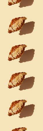 Vertical banner seamless pattern levitating freshly baked buttery croissant with frangipane almond sprinkled with nut petals beige background with hard shadow. Coffee, pastry shop breakfast concept.の写真素材
