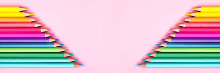 Banner with macro wooden pastel multicolored pencils on pink background, top view with copy-space....