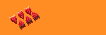 Banner Halloween diagonal pattern jelly beans in the shape of devil head close-up on an orange...