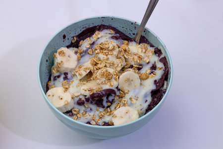 AÃ§aÃ­ with condensed milk powdered milk and granola and bananas in a blue pot with spoonの写真素材