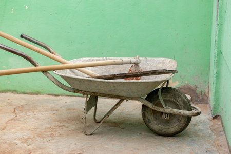 Old metal wheelbarrow with dirty cement hoeの写真素材