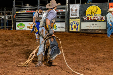 Itaja, Goias, Brazil - 04 22 2023: Person at a bull riding event in a rodeo arena at nightのeditorial素材
