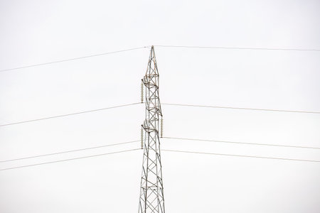closeup on electric power transmission line pole with white sky in backgroundの写真素材