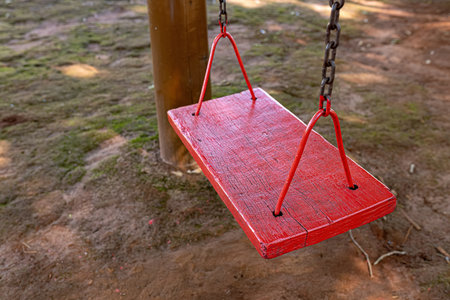wooden and metal playground swing suspended by chain selective focusの写真素材