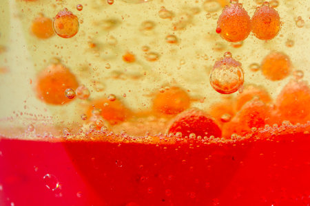 glass with drops of colored bubbles in water and oilの写真素材