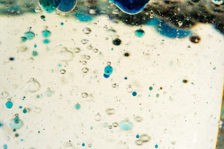 glass with drops of colored bubbles in water and oilの写真素材