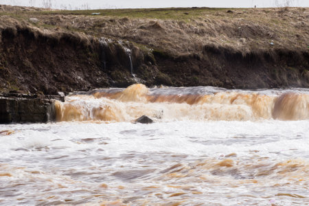 waterfall on the river with rocky shore in the spring and summer