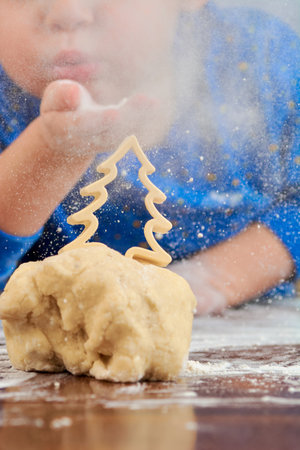 the baby blows flour on the Christmas tree on the test making cookiesの写真素材