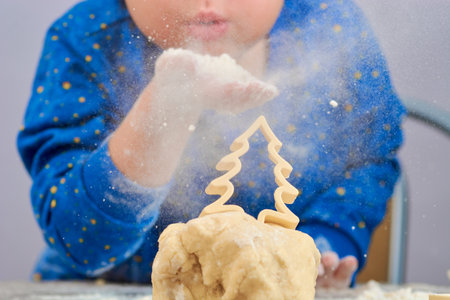 the baby blows flour on the Christmas tree on the test making cookiesの写真素材