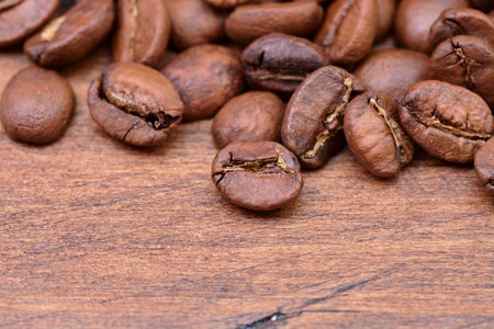 coffee beans on a wooden background scattered from the bagの写真素材