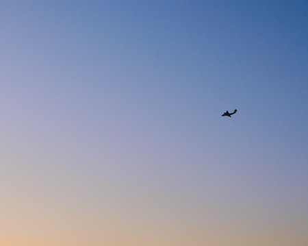the plane flies high in the sky and the sun at sunsetの写真素材