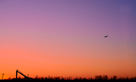 the plane flies high in the sky and the sun at sunsetの写真素材