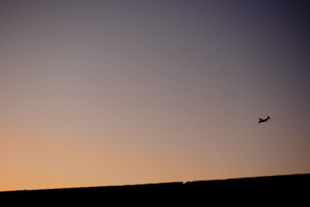 the plane flies high in the sky and the sun at sunsetの写真素材