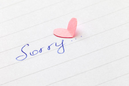 Handwritten word Sorry with heart. Shallow depth of field.