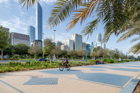Man riding bike on Abu Dhabi Corniche in the morning with modern cityscape at the background. Active lifestyle.のeditorial素材