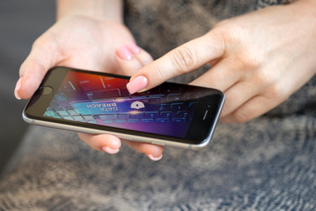 Mobile phone in female hands with screen showing compromised virus infected device. Cyber attack.の写真素材