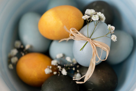 Baby blue, yellow and dark grey Easter eggs in a bowl, top view macro closeup with shallow depth of field. Festive decoration.の写真素材