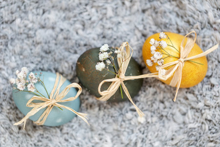 Baby blue, dark grey and yellow Easter eggs with spring flowers. Festive decoration.