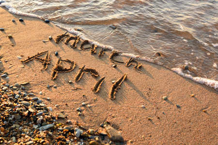 April is coming concept - inscription March and April on a beach sand, the wave is almost covering the word Marchの写真素材