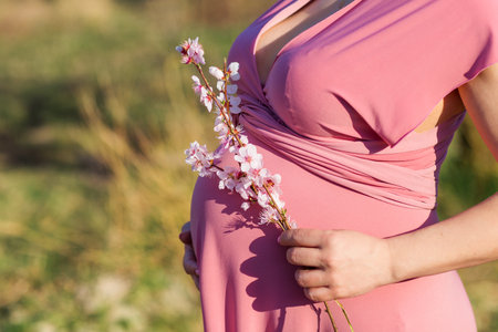 Pregnant happy girl in blossom peach gardenの写真素材