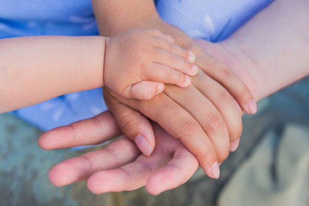 Concept of unity, support, protection, happiness. Child hand closeup into parents. Hands of father,...