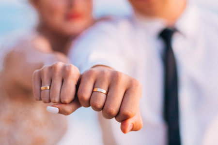 Newly married couple holding closed fists with wedding rings.の写真素材