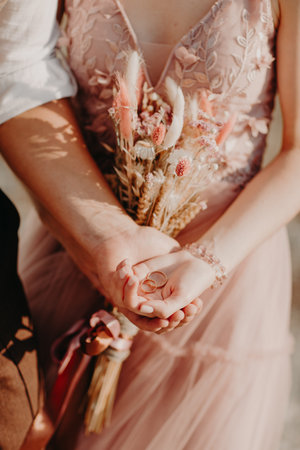 gold wedding rings in the couple hands on flowers backgroundの写真素材