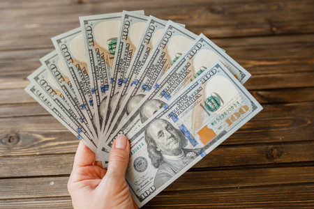 woman hand with dollars isolated on wooden background.の写真素材
