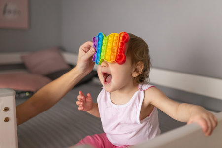 A little girl is playing with a popping toy. An exciting sensory toy for development.の写真素材
