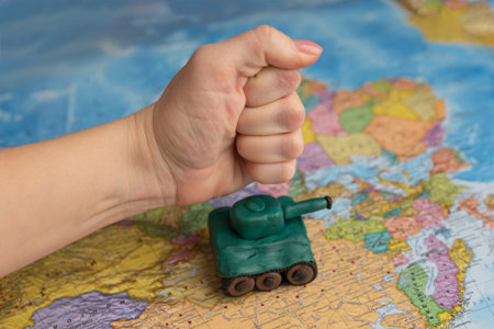 A little boy punches a tank on the background of a map of the worlds. A symbol of peace. stop war. no warの写真素材
