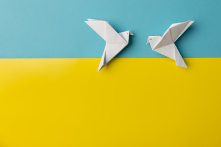 Two white birds as a symbol of peace on blue and yellow pastel paper color for background.の写真素材