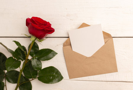 Red rose with craft envelope and greeting card on wooden white background.の写真素材