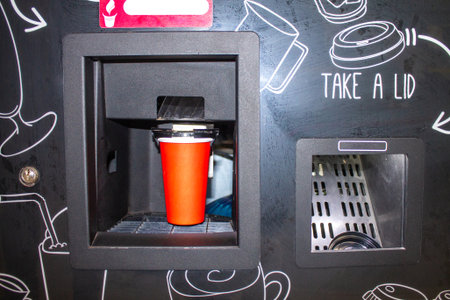 Coffee machine preparing fresh coffee and pouring into red cups at a shopping mall, bank, store or airport.の写真素材