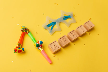 Creative minimalistic concept for April Fools' Day. wooden letters 1 april and festive decor on the yellow background.の写真素材