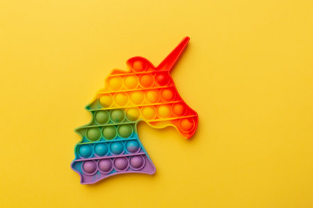 Rainbow Square Fidget Toy on the yellow background. Popular Relaxing square shape silicone stress relief toy.の写真素材