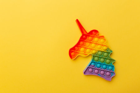 Rainbow Square Fidget Toy on the yellow background. Popular Relaxing silicone stress relief toy in the shape of a colorful horse.の写真素材