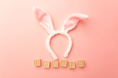 Bunny ears and wooden letters Easter on a pink background, top view. happy easter.