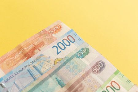 Money of Russia. Banknotes and coins on yellow background. Close-up of Russian rubles of various...