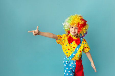 Funny kid clown against blue background. Happy child playing with festive decor. 1 April Fool's day concept.の写真素材