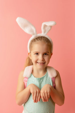 Beautiful cute little girl in Easter bunny ears smiling on a pink background. Easter postcard.の写真素材