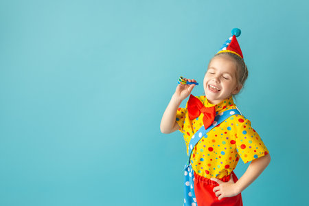 Funny kid clown against blue background. Happy child playing with festive decor. Birthday and 1 April Fool's day concept.の写真素材