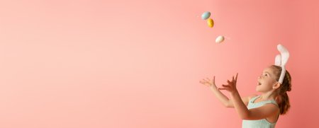 Beautiful cute little girl in Easter bunny ears with colorful easter eggs on a pink background. Easter postcard.の写真素材