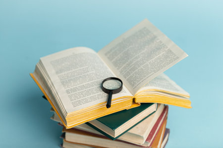Vintage book and magnifying glass on light blue background. education background.の写真素材