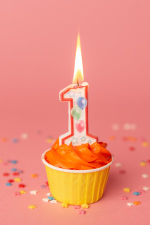 Number 1 candle in a cupcake against a pastel pink background. First bithday cake.の写真素材