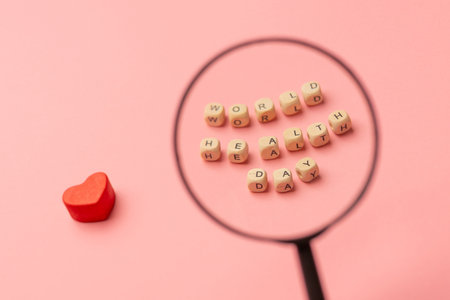World Health Day, medical and healthcare. Red heart and close-up text World Health Day under a magnifying glass on pink background.の写真素材