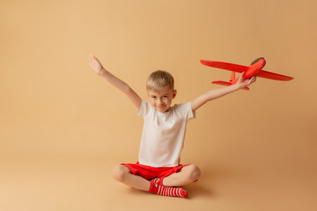 Adorable little boy playing with red airplane on the light background. Children and entertainment concept.の写真素材