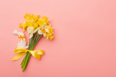 Light yellow spring bouquet and easter bunny on pink background. Spring flowers background with copy space.の写真素材