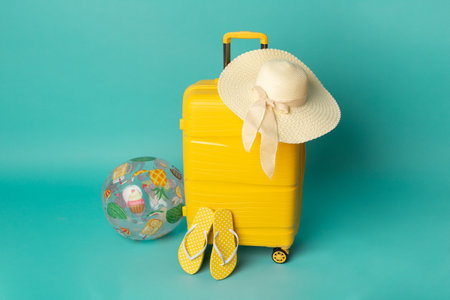 Yellow suitcase with flip flops and hat on blue background. travel concept. minimal style.の写真素材